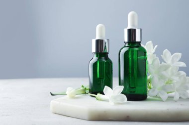 Açık gri masada gerekli yağlar ve yasemin çiçekleri, yakın plan. Metin için boşluk