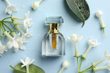 Parfüm ve yasemin çiçekleri açık mavi arka planda, düz yerde