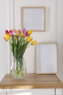 Bir buket güzel lale ve çerçeve kapalı bir masa üzerinde.