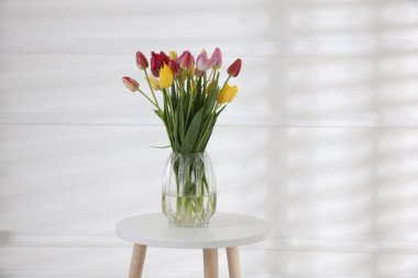 Beyaz duvarın yanındaki masada bir buket güzel lale