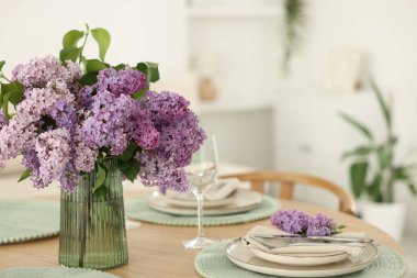Güzel leylak çiçekleri, tabaklar, çatal bıçak takımı ve cam kaplama masa.