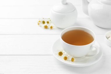 Fincanda nefis papatya çayı, taze çiçekler ve beyaz ahşap masada çaydanlık, yakın plan. Metin için boşluk