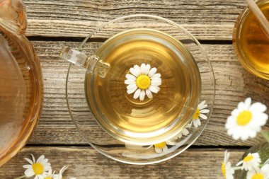 Cam bardakta nefis papatya çayı, taze çiçekler, bal ve çaydanlık ahşap masada, düz uzanmış