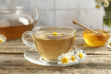 Cam bardakta nefis papatya çayı, taze çiçekler, ahşap masada bal ve çaydanlık, yakın plan.