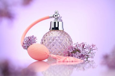 Bir şişe parfüm ve ayna yüzeyinde eflatun rengine karşı leylak çiçekleri, seçici odak