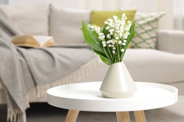 Bir buket güzel vadi zambağı vazoda, kahve masasının üstünde.