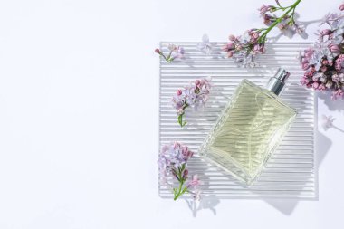 Bir şişe parfüm ve beyaz arka planda güzel leylak çiçekleri. Metin için boşluk