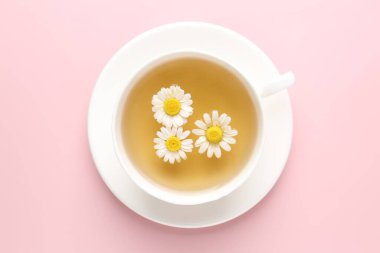 Fincanda nefis papatya çayı ve pembe arka planda taze çiçekler.