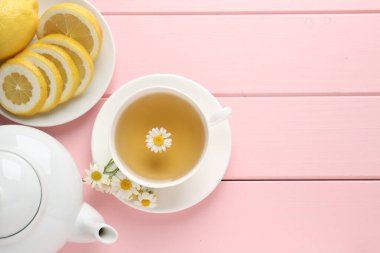 Fincanda nefis papatya çayı, taze çiçekler ve pembe ahşap masada limon, düz yatak. Metin için boşluk