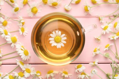 Cam fincanda nefis papatya çayı ve pembe ahşap masada taze çiçekler.