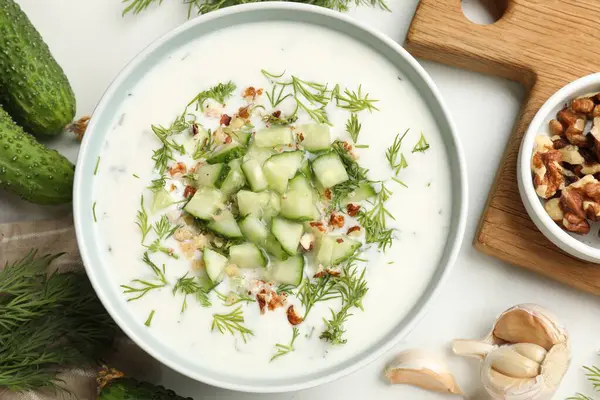 Salatalık çorbası ve kabın içinde fındık, beyaz masada ürünlerin arasında, düz yerde.