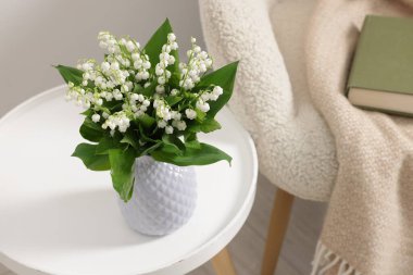 Vadinin güzel zambaklarından oluşan bir buket vazo, kahve masasının üstünde, içerideki koltuğun yanında.