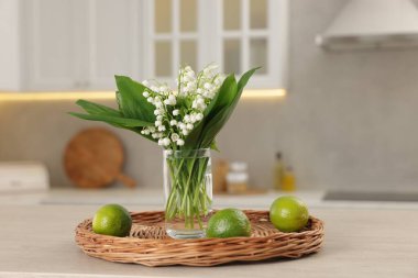 Güzel bir zambak buketi ve mutfaktaki ahşap masa üzerinde limon, yakın plan.