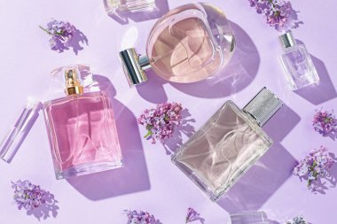 Lüks parfümler ve açık mor arka planda güzel leylak çiçekleri.