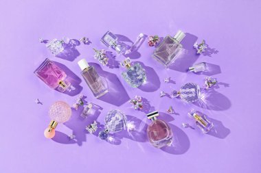 Düz kompozisyon, parfüm şişeleri ve mor arka planda leylak çiçekleri vardı.