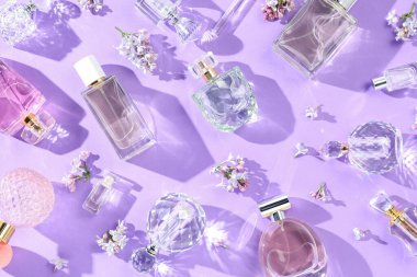 Düz kompozisyon, parfüm şişeleri ve mor arka planda leylak çiçekleri vardı.