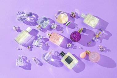 Düz kompozisyon, parfüm şişeleri ve mor arka planda leylak çiçekleri vardı.