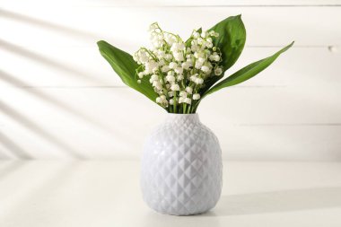 Vadi çiçeklerinin güzel zambakları beyaz masadaki vazoda.