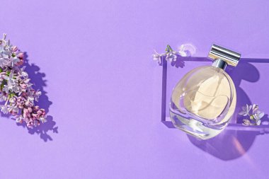 Düz kompozisyon, mor arka planda parfüm şişesi ve leylak çiçekleri vardı. Metin için boşluk