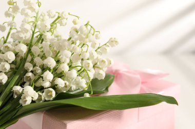 Vadi çiçeklerinin güzel zambakları ve beyaz masada hediye, yakın plan. Metin için boşluk