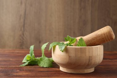 Taze limon merhemi yaprakları, ahşap masada tokmak ve havan topu, yakın plan.