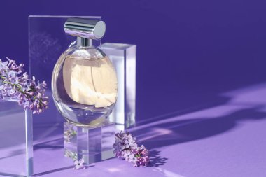 Mor arka planda parfüm şişesi ve leylak çiçeklerinin şık sunumu, yakın plan. Metin için boşluk