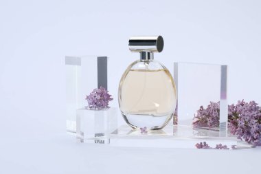 Açık gri arka planda parfüm şişesi ve leylak çiçeklerinin şık sunumu, yakın plan