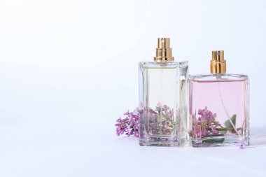 Parfüm şişeleri ve açık gri arka planda leylak çiçekleri olan bir dal. Metin için boşluk