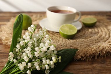 Vadi çiçeklerinin güzel zambakları, ahşap masada çay ve limonlar, yakın plan.