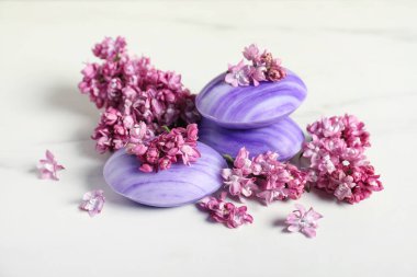Sabun çubukları ve leylak çiçekleri beyaz masada, yakın plan.
