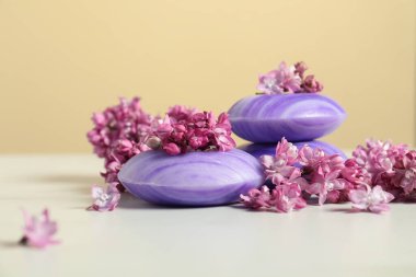 Sabun çubukları ve leylak çiçekleri beyaz masada bej arka planda, yakın plan