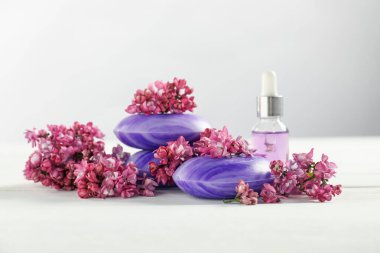 Sabun çubukları, temel yağ ve leylak çiçekleri beyaz masada, yakın plan.