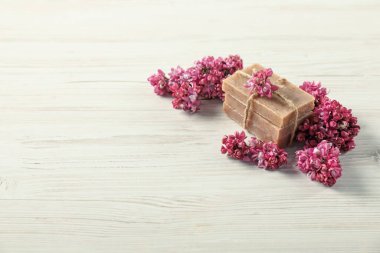Hafif ahşap masada bir yığın sabun ve leylak çiçeği. Metin için boşluk