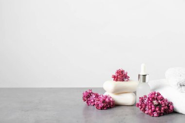 Bir yığın sabun, temel yağ ve leylak çiçekleri gri desenli masa ve açık arkaplan. Metin için boşluk