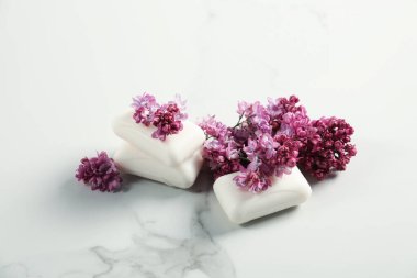 Sabun çubukları ve leylak çiçekleri beyaz mermer masada, yakın plan.