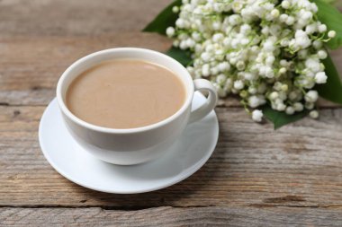 Bir buket güzel vadi zambağı çiçeği ve ahşap arka planda kahve, yakın plan.