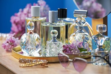 Parfüm şişeleri, aksesuarlar ve ahşap masada leylak çiçekleri, yakın plan.