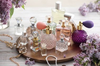 Beyaz ahşap masada parfüm, aksesuar ve leylak çiçekleri.