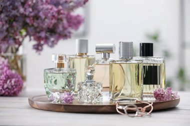 Beyaz ahşap masada parfüm şişeleri ve leylak çiçekleri.