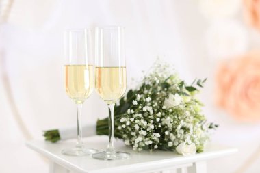 Şampanya bardakları ve düğün buketi kapalı bir masada, yakın plan.