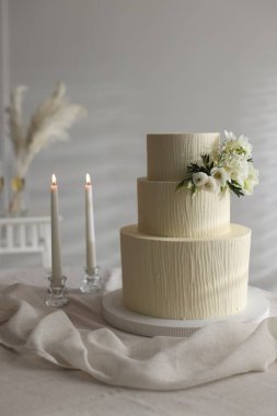 Çiçek desenli nefis düğün pastası ve içeride yanan mumlar.