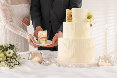 Yeni evliler, bir parça düğün pastasıyla tabağı evin içindeki masaya koyuyorlar.