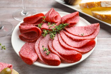 Hafif ahşap masada servis edilen kekik dilimli lezzetli sosisler.