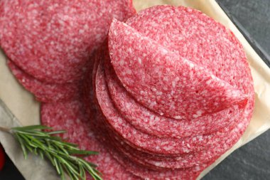 Lezzetli tütsülenmiş sosis ve biberiye dilimleri siyah masada, üst tarafta.