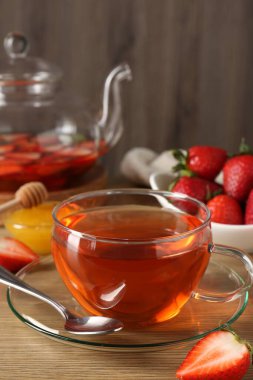 Çilekli Aromatik meyve çayı ve ahşap masada bal, yakın plan.
