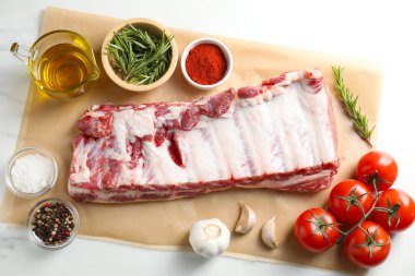Çiğ domuz kaburgası, baharatlar ve domatesler beyaz masada, düz yerde.