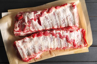 Siyah ahşap masada deniz tuzu ve çiğ domuz pirzolası.