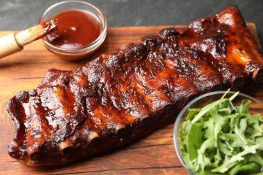 Lezzetli kızarmış domuz pirzolası, yanında roka ve siyah masada sos, yakın plan.