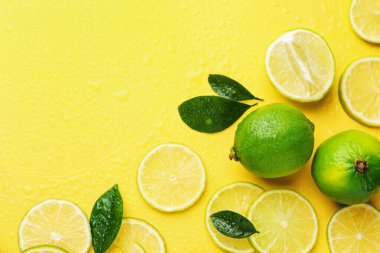 Taze limon ve yeşil yapraklar sarı arka planda, düz yerde. Metin için boşluk