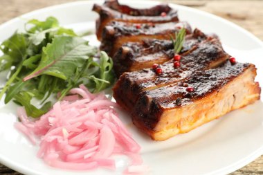 Lezzetli pirzola, soğan ve roka ahşap masada, yakın plan.